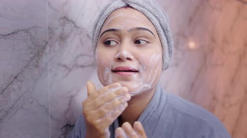 Female Cleansing Face with Foam Cleanser During Morning Skincare Routine.