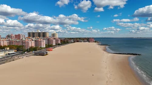 Aerial View of Sandy Beach and Coastal City Under a Blue Sky A Scenic Aerial View Showcasing a Vast