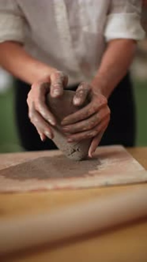 Smiling Craftsperson in White Shirt Shaping a Soft Clay Bowl in a Bright Ceramics Workshop