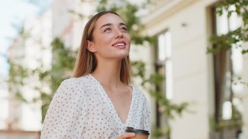 Woman Enjoys Coffee Walking on a City Street
