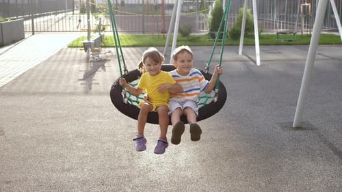 Children Swinging Together on Playground Tire Swing