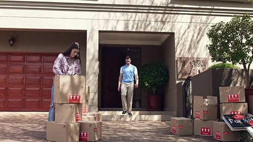 Couple Moving Boxes into New Suburban Home
