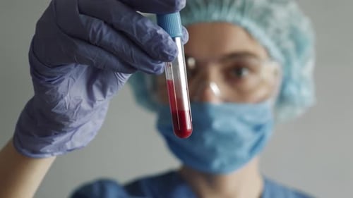 Woman Holding Vial of Blood in Hospital Setting