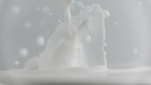 Goutte de lait frais tombant et éclaboussant dans un bassin laiteux déversant du lait au ralenti
