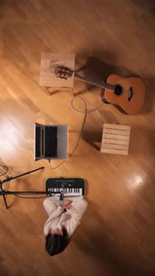 Vertical Video Young Woman Sitting on a Wooden Floor Surrounded By Musical Instruments and Recording