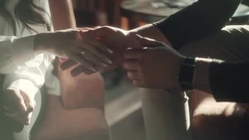 Man and Woman Stack Hands Inside by Sunlight