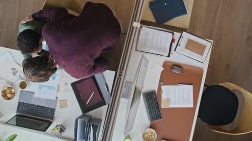 Vue de dessus des collègues travaillant à des bureaux avec cloison vitrée