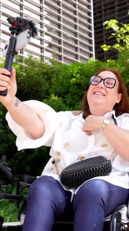 Influencer creating content with mobile phone and microphone on wheelchair