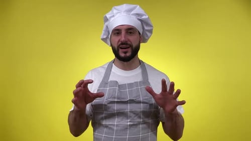Chef masculino explicando la receta de la comida ante la cámara aislado en amarillo