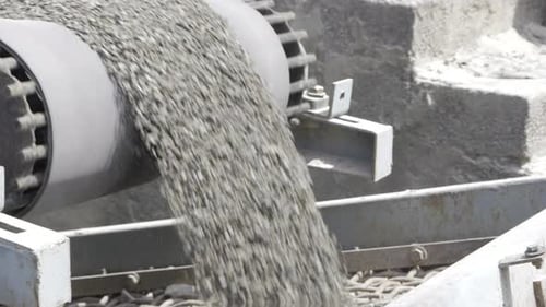 Gray Rocks Falling from Conveyor Belt on Wire Screen
