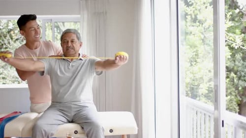 Physical Therapist Assists Senior Man With Exercise