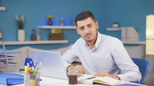 Home office worker man looking emotional at camera.