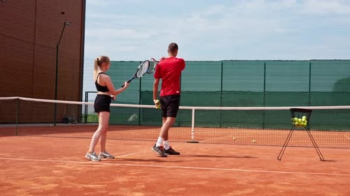 Man and Woman Playing Tennis on Outdoor Court