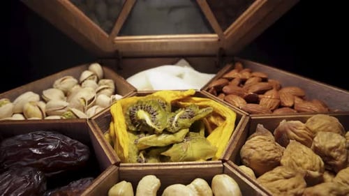 Open a wooden box with dried fruits and nuts. Close-up, in motion