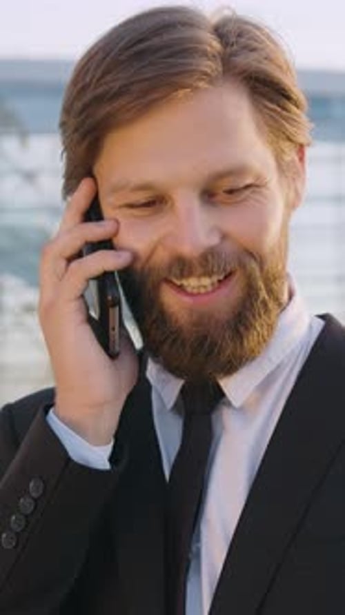 Smiling Man in Suit Talking on Phone Outdoors