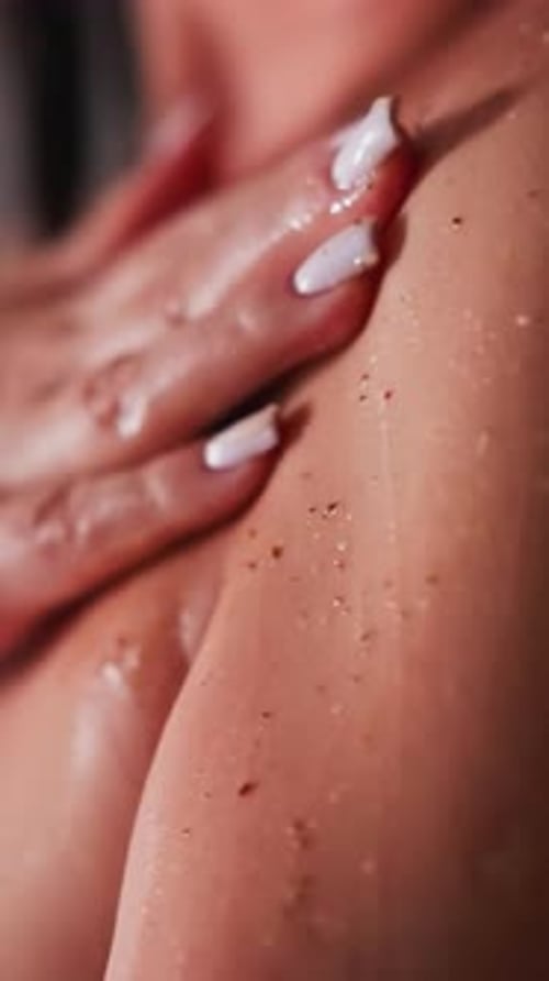 Une femme étale un gommage sur la peau dans l'unité de douche