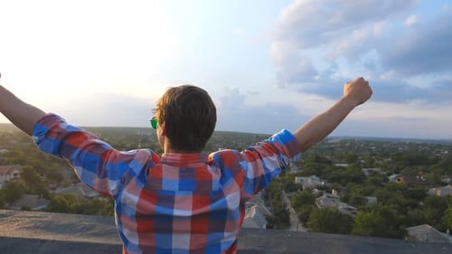 Man Reaching Upward on Rooftop at Sunset