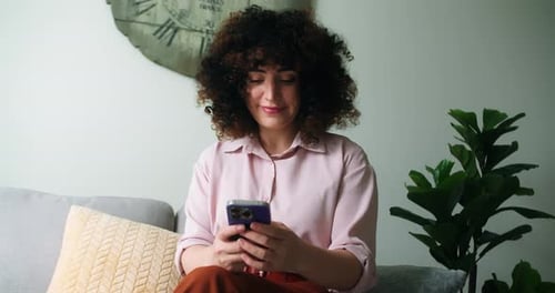 Woman Using Mobile Phone on Sofa at Home