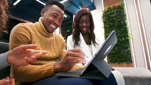 Multiracial group of workers in an office discussing business using a tablet. Slow motion