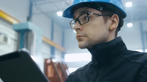 Operário de fábrica com capacete está usando um tablet.