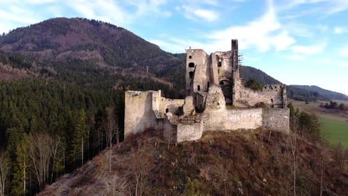Ruins of a medieval castle from the front of a drone in the middle of the mountains of a Slovakian l