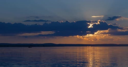 Golden Sunset Over Serene Lake With Distant Boat