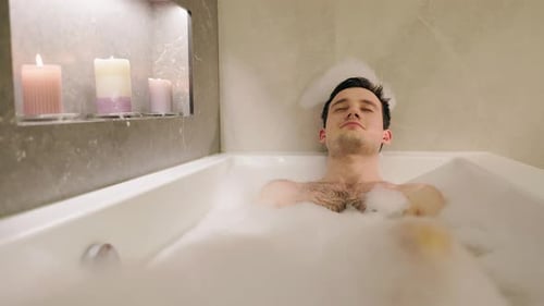 Relaxed Young Man Soaking in a Bubble Bath