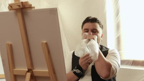 Jeune artiste masculin toxicomane reniflant un paquet de colle