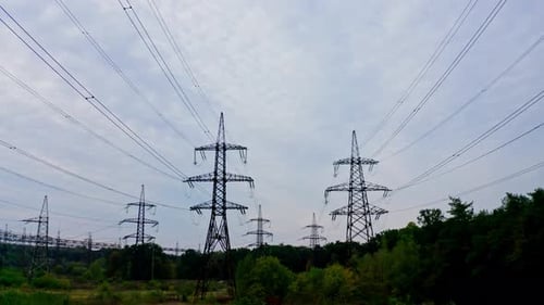 Electrical transmission lines over green grass. Power lines in the beautiful landscape of nature.