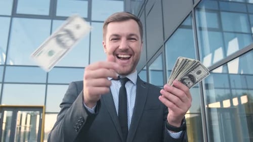 A Rich Man Scatters Dollar Bills and Smiles at the Camera Business and Finance Concept A Rich Man