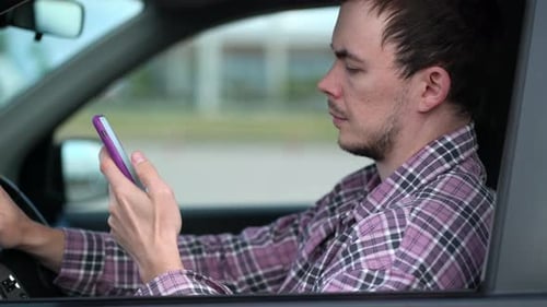 Man Using Smart Phone in a Car