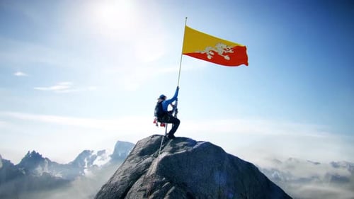 Alpiniste tenant le drapeau du Bhoutan au sommet de la montagne