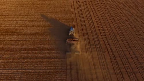 Sowing fields with tractor and seeder in dusty field aerial view