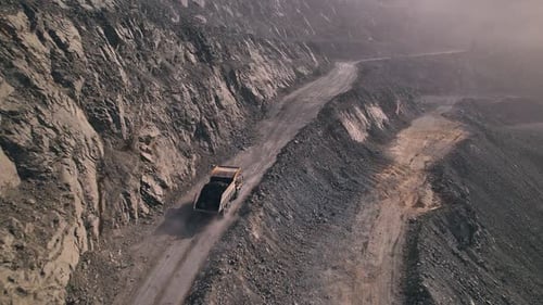 Luftbild von oben mit Verkabelung: Großer gelber Muldenkipper bei der Arbeit, Bewegung in einem Steinbruch, Eisenerzabbau, groß