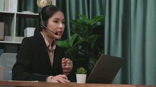 Woman with Headset Working at Laptop in Office