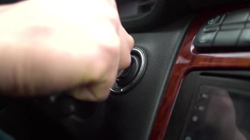Man hand put an ignition key and starts the car.