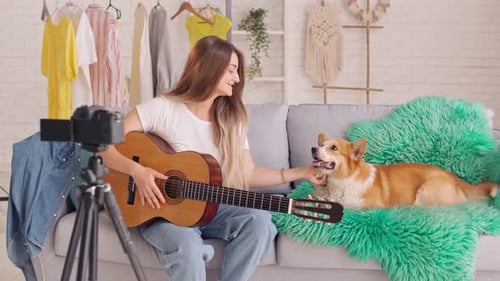 Woman Playing Guitar with Dog on Couch