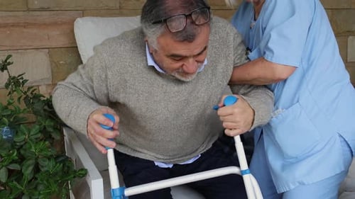 Caregiver Helping Senior Man With Walking Frame