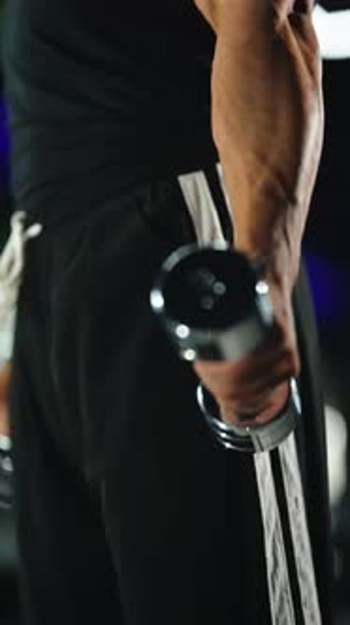 Closeup of a Muscular Athlete Executing a Controlled Dumbbell Bicep Curl with a Chrome Weight in a