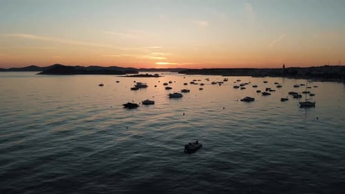 Drone shot of coast line with boats in the water with sunset in the background. Harbor at sunset.