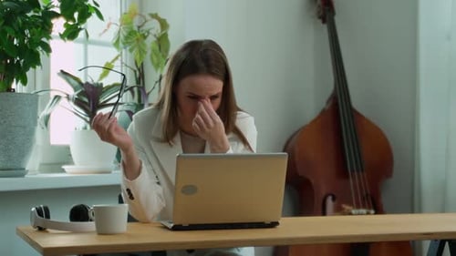 An Overworked Tired Woman Holds Glasses in Her Hands and Touches the Bridge of Her Nose A Female