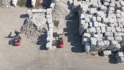 Aerial top down of tractor excavator moving cube plastic waste trash inorganic pollution in dump lan