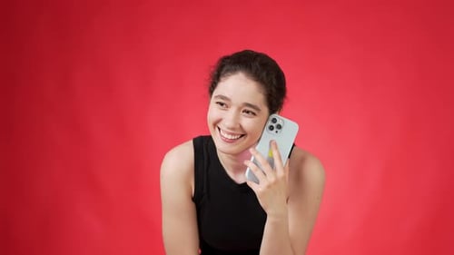 Smiling Woman Chatting on Cellphone Against Red Backdrop