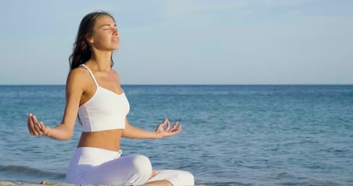 Beautiful woman doing yoga at sea, harmony and freedom, background of the sea and sand, concept of