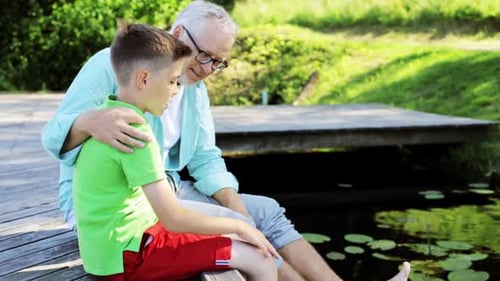 Grandfather and grandson share a summer moment talking by the river