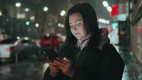A Girl on the Background of a Rainy Night City Writes a Message