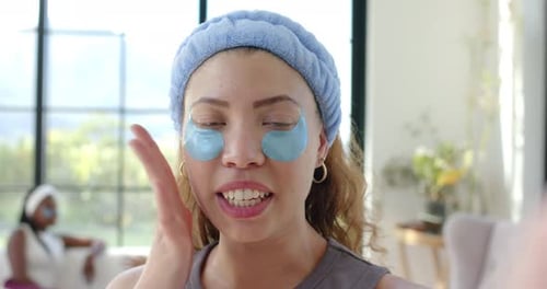 Mujeres afroamericanas, un tutorial sobre cómo mirar mientras usan parches azules de hidrogel en la sala de estar