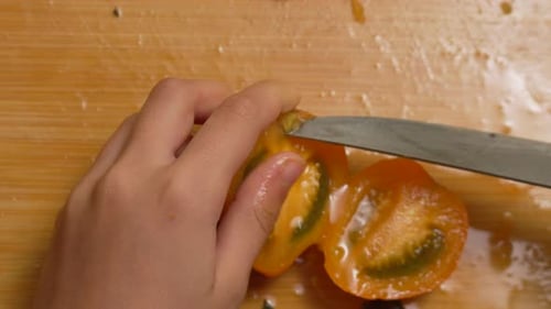 Child Carefully Slicing Fresh Tomato on Cutting Board