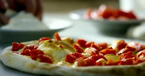 Close up of a pizza chef's hands filling a pizza with high quality Italian gastronomic ingredients