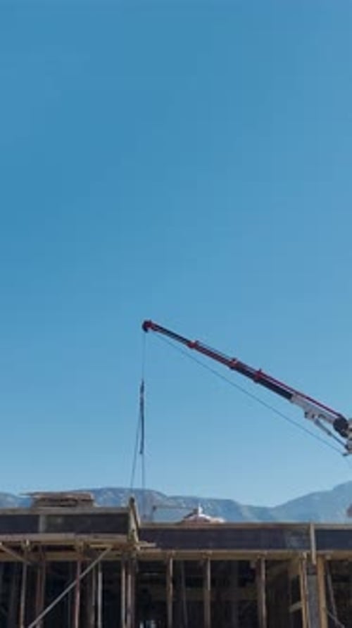 Vertical Video HighAngle Shot of a Construction Project with Cranes Lifting Materials and Workers in